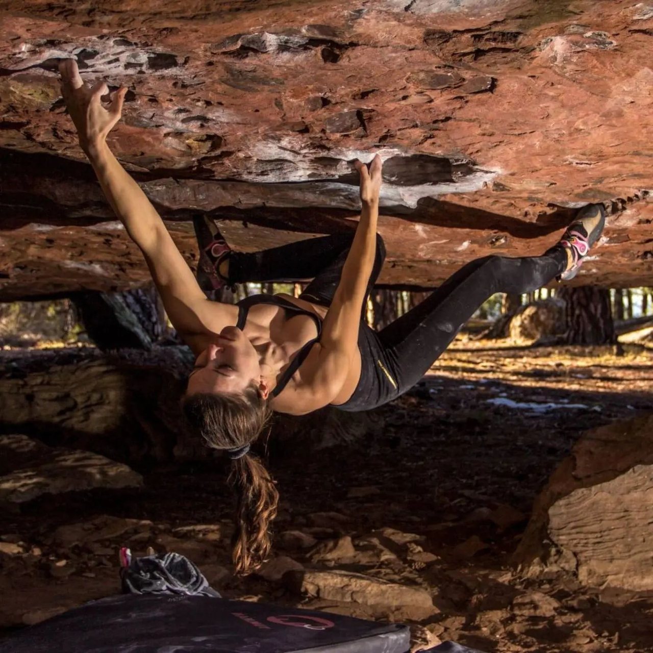 Melanie Kaiser bouldering upside down beneath an overhanging sandstone roof.