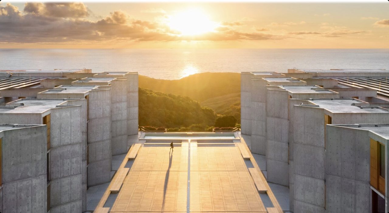 The Salk Institute courtyard looking west into a low sun, the towers in silhouette on either side.